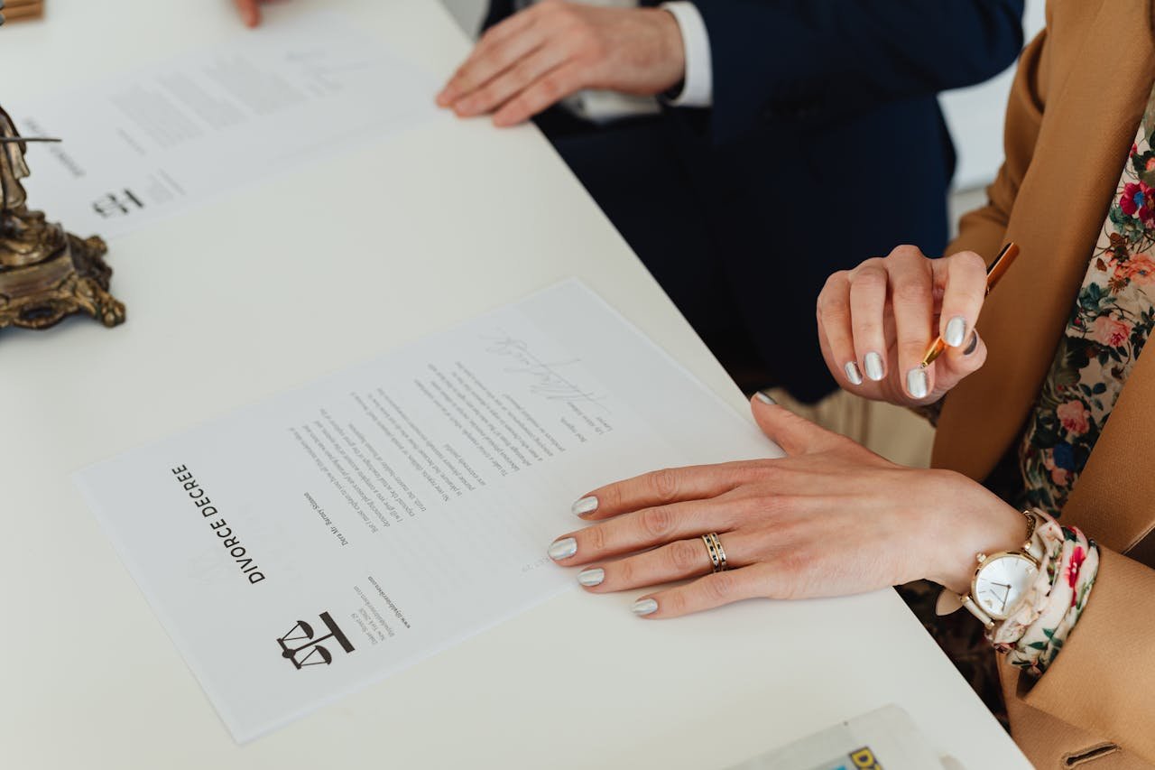 A detailed view of hands signing a divorce decree document at an indoor office meeting.
