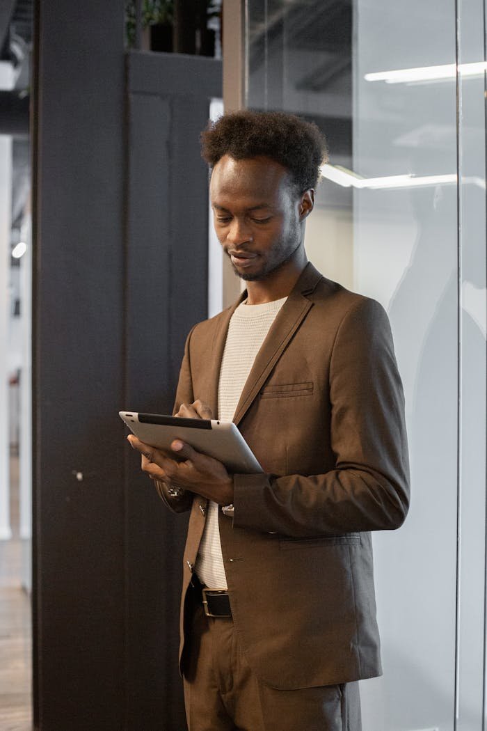 Confident businessman in formal attire using a digital tablet indoors.